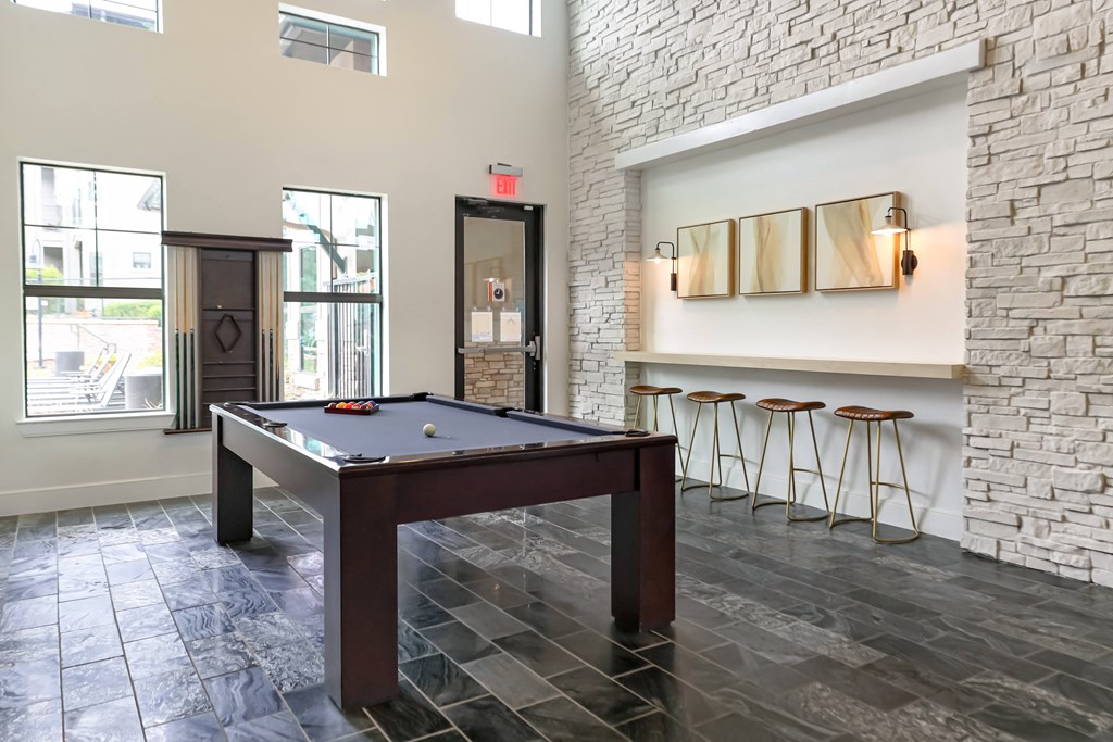 a billiards table in a game room with stools