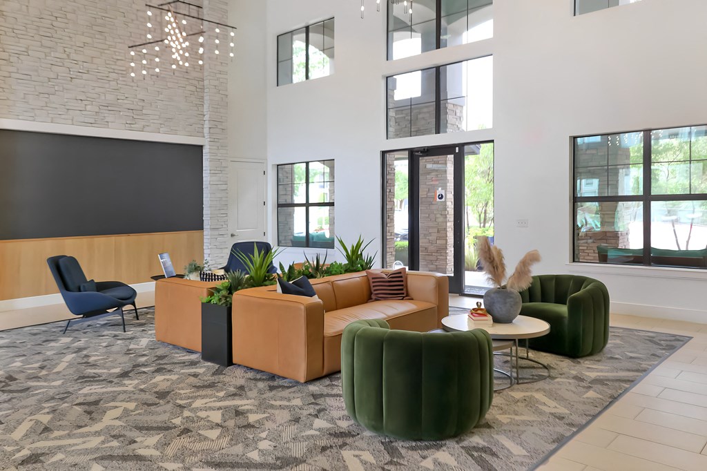 a living room with couches and chairs in a building with tall windows