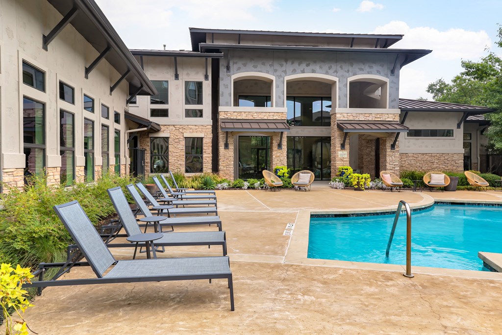 a swimming pool with chaise lounge chairs in front of a building