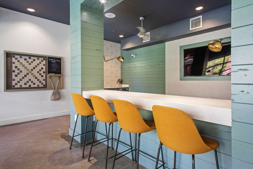 a long bar with yellow chairs in front of a blue wall