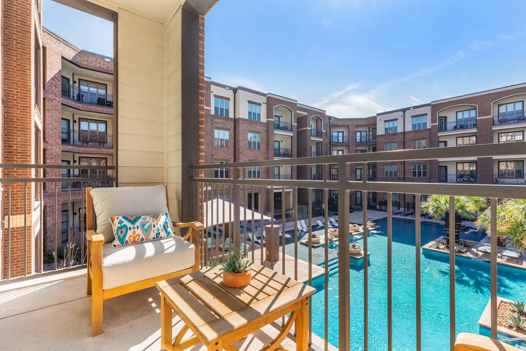 a balcony with a pool and an apartment building in the background
