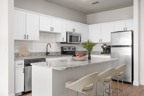 A kitchen with white cabinets and a granite countertop.
