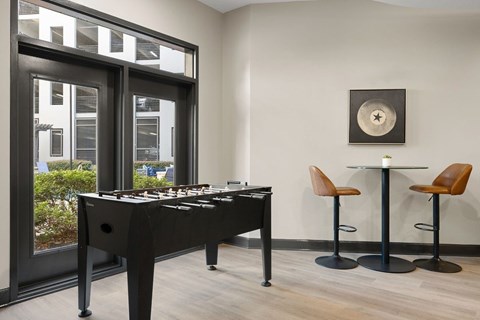 A black pool table with a white cloth and a light brown leather chair.