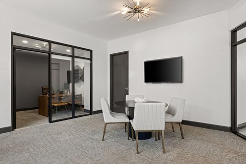 A modern dining room with a glass door and a flat screen TV on the wall.