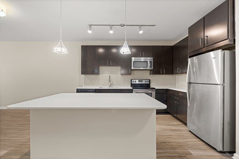 A modern kitchen with a white island and stainless steel appliances.