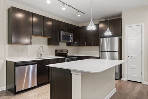 A modern kitchen with dark brown cabinets and stainless steel appliances.