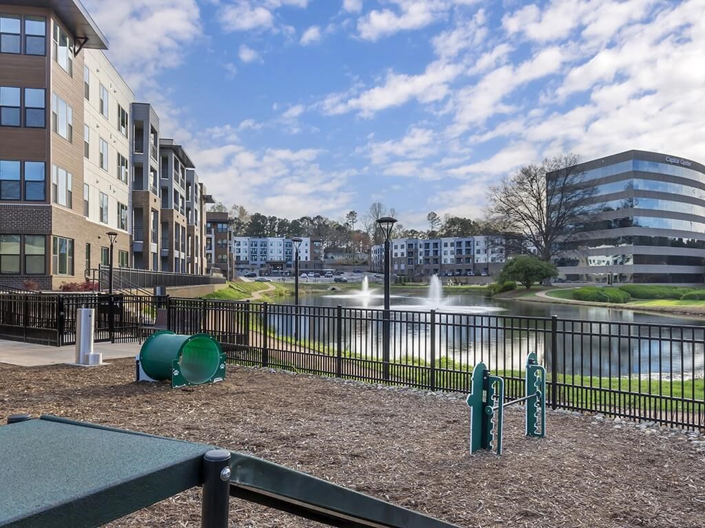 a playground in front of a pond with buildings in the background