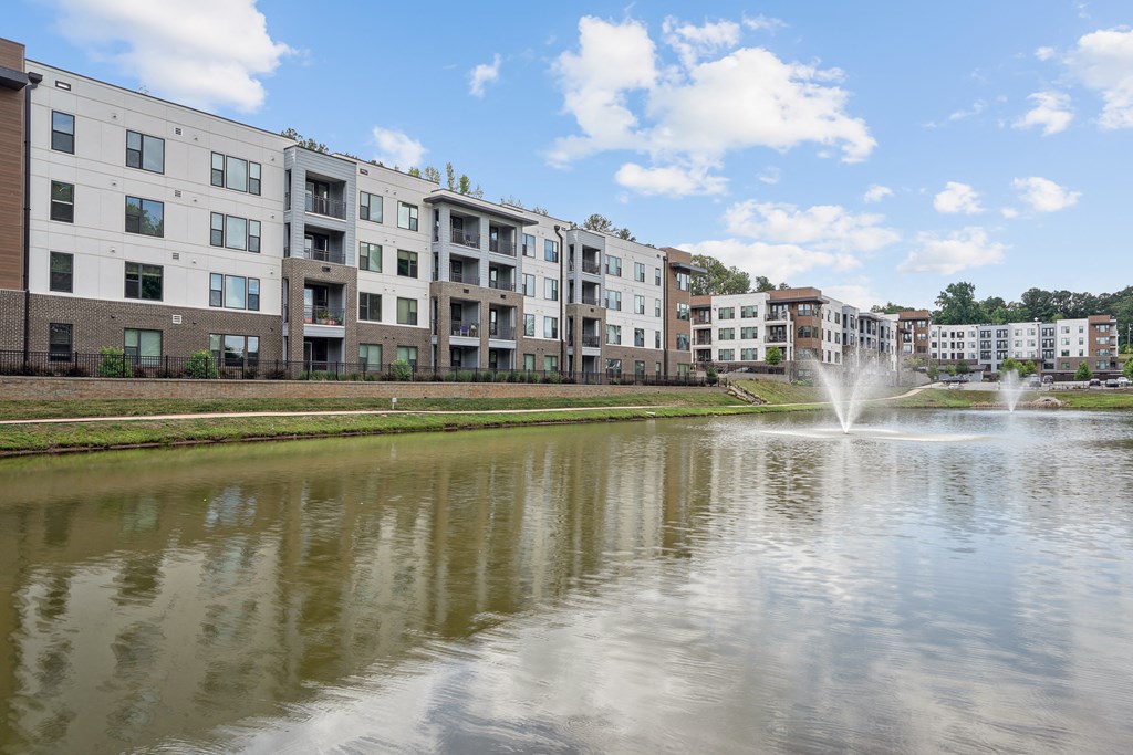 a pond with a fountain in front of an apartment building