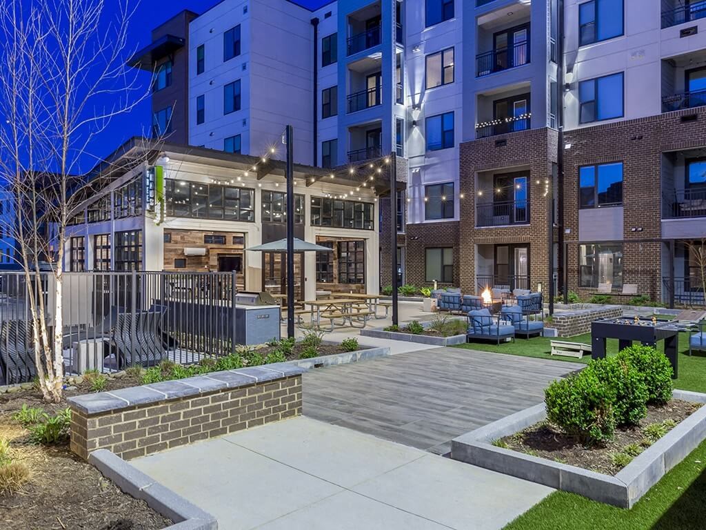 a patio with a firepit and benches in front of a building