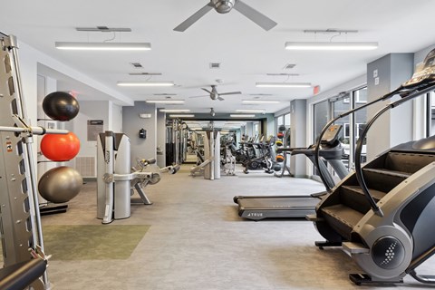 a gym with treadmills and other exercise equipment in a building with glass walls