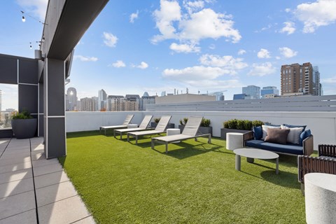 a roof top patio with lawn chairs and a view of the city