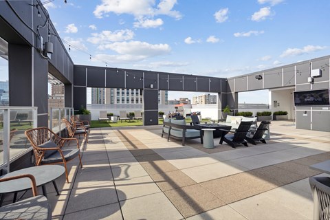 a rooftop patio with a table and chairs and a tv