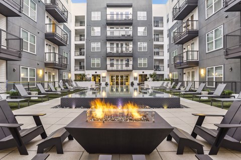 an open courtyard with a fire pit in front of an apartment building