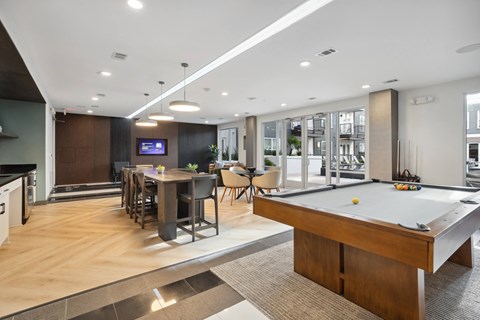 a communal area with a pool table and a dining table with chairs and a television