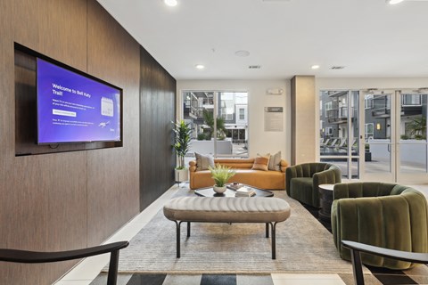 a lobby with couches and chairs and a tv on the wall