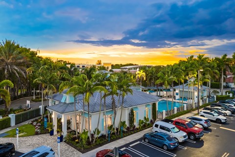 A sunset view of a parking lot with cars and a pool.