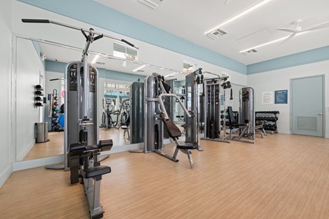 A gym with a variety of equipment including treadmills, weights, and exercise machines.