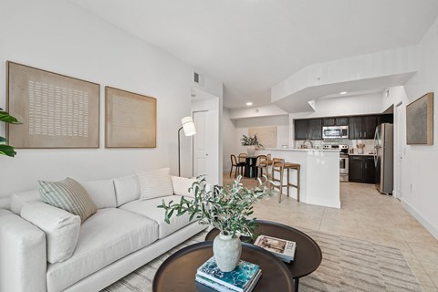 A living room with a white couch and a coffee table with a plant on it.