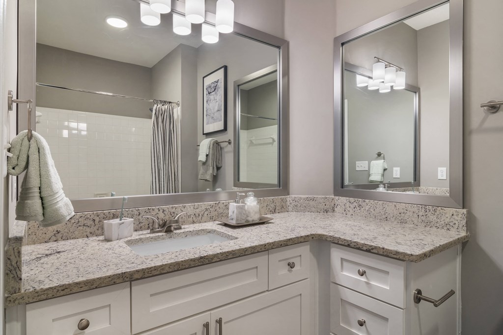 a bathroom with white cabinets and a granite counter top