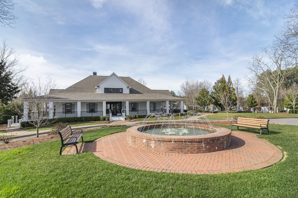 a park with a fountain in front of a house
