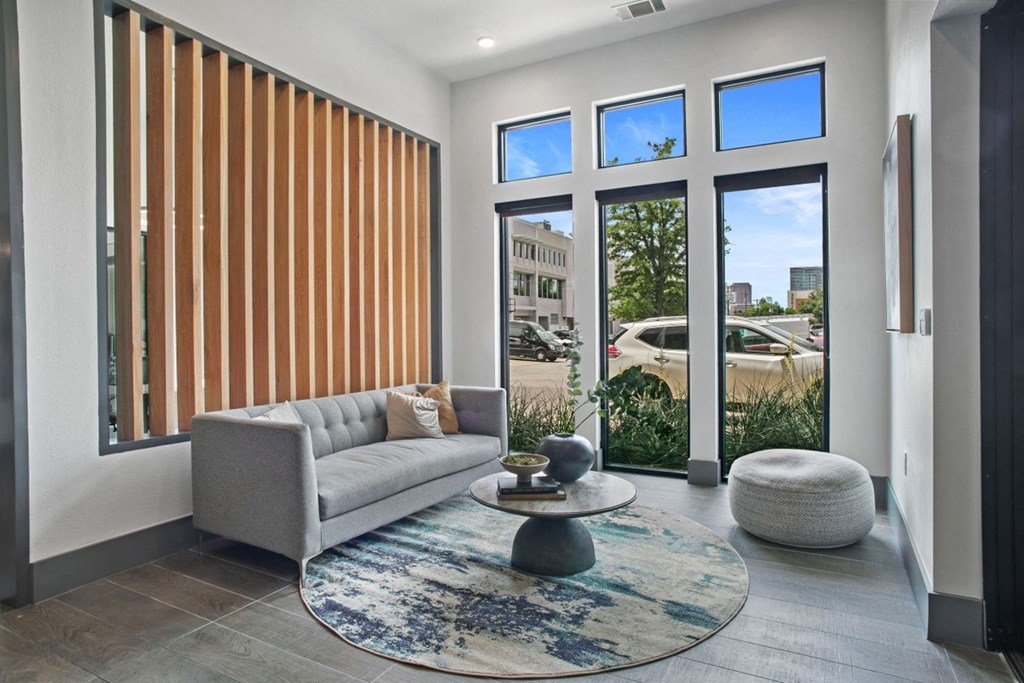 a living room with a gray couch and a round coffee table on a blue rug
