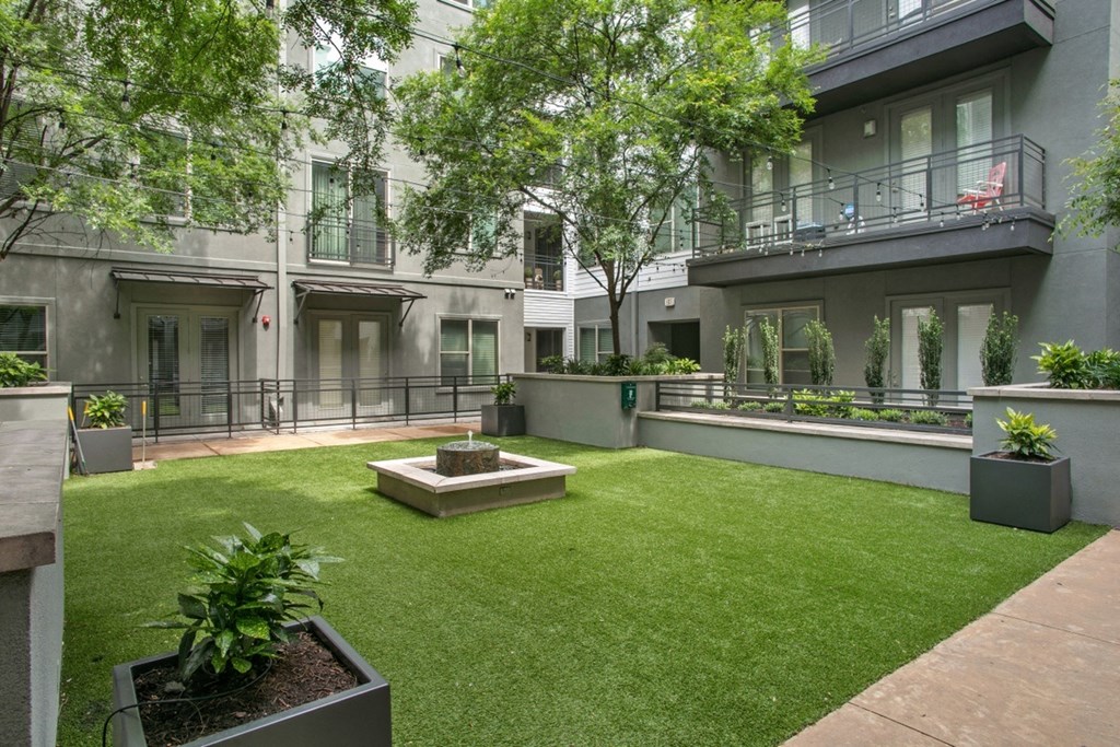 a courtyard with grass and trees in front of a building