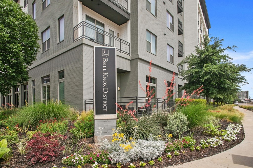 an apartment building with a flower garden in front of it