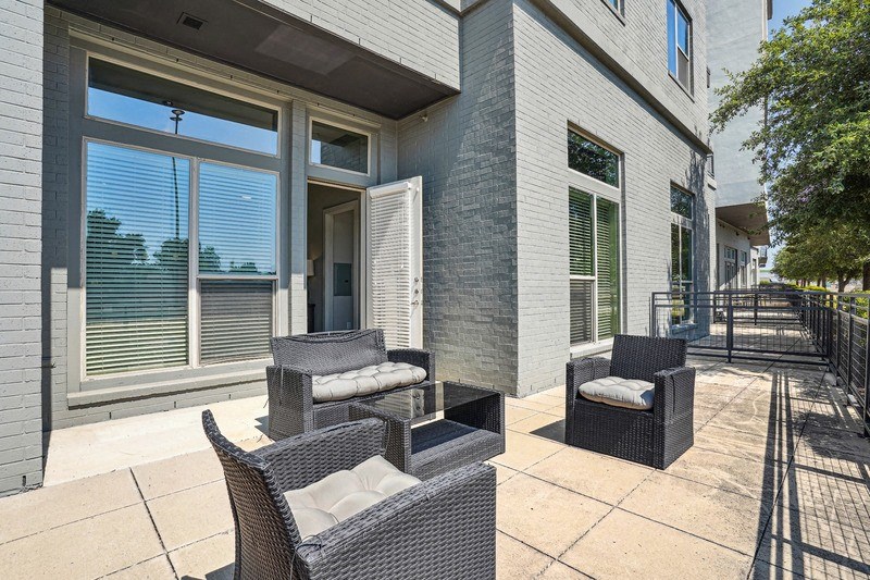a patio with chairs and a table in front of a building