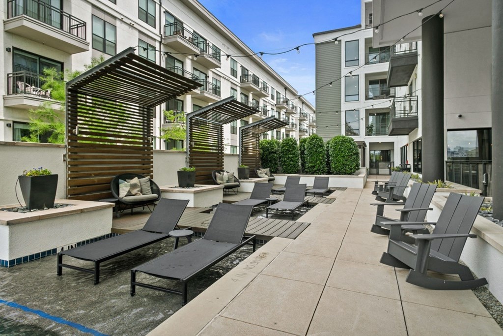 an outdoor patio with lounge chairs and fire pits at the district flats apartments in lenexa