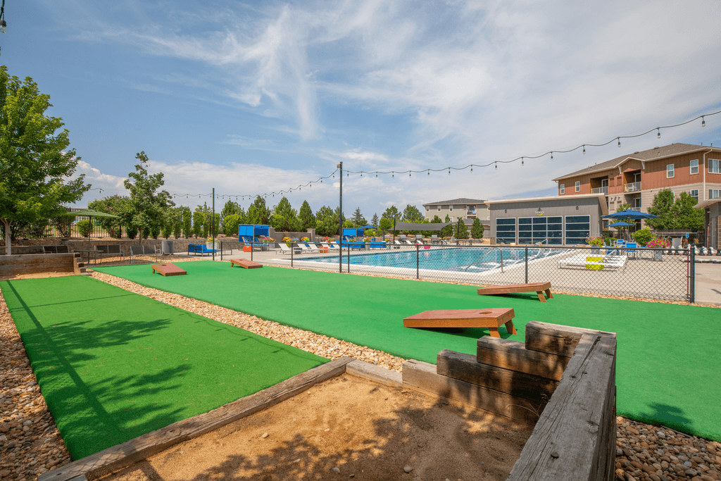 A playground with a green surface and a wooden bench.
