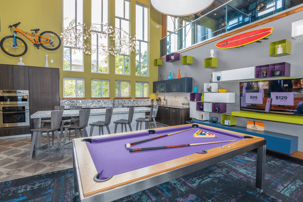 A pool table in a room with a bicycle on the wall.