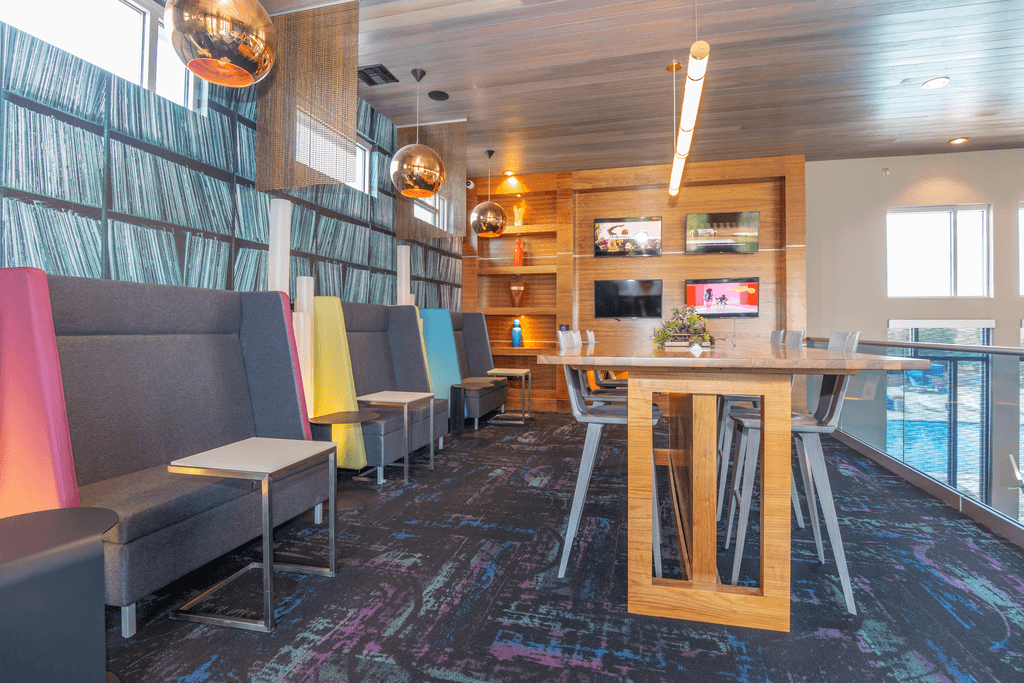 A room with a long table and chairs with a TV on the wall.