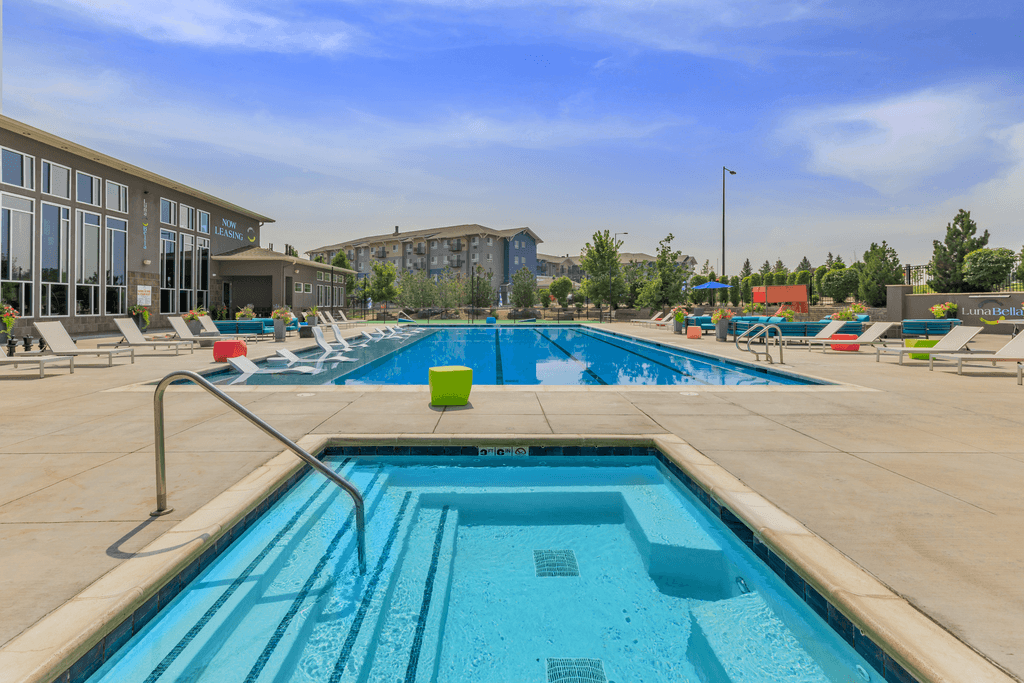 A large swimming pool with a diving board and lounge chairs.