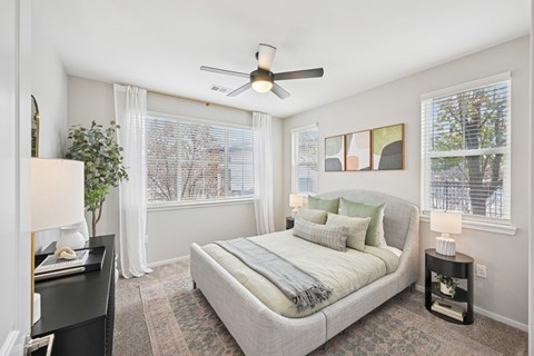 A bedroom with a bed, nightstand, and a ceiling fan.