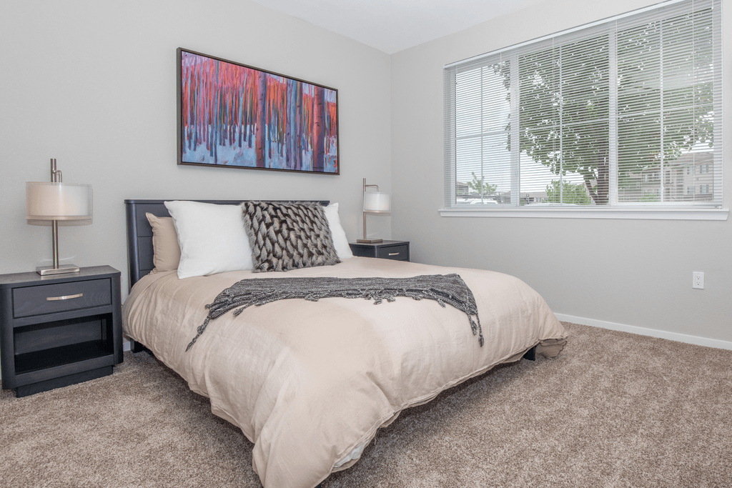 A bedroom with a large bed and a painting on the wall.