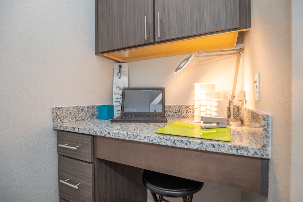 A modern desk with a laptop, a cup, and a notepad on a marble countertop.