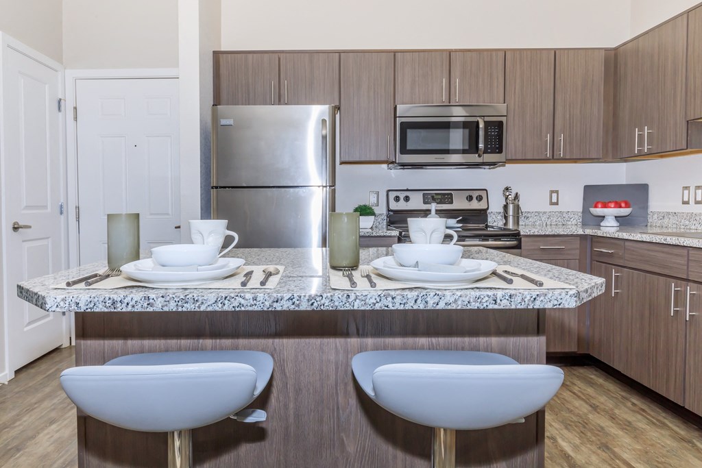 A kitchen with a granite countertop and stainless steel appliances.