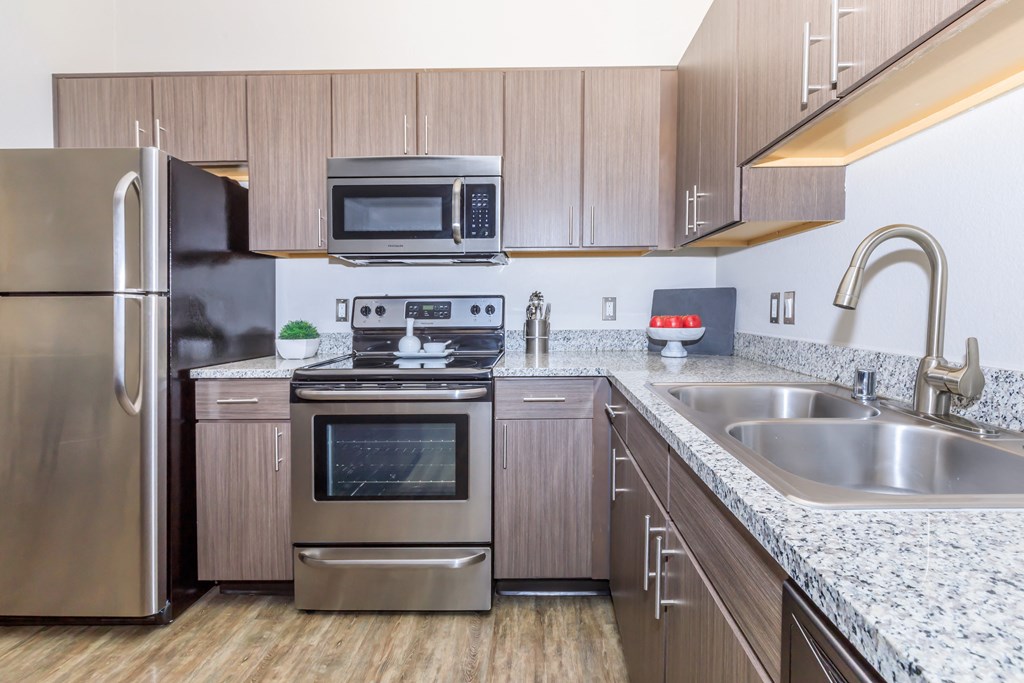 A modern kitchen with a stainless steel refrigerator, microwave, oven, and sink.