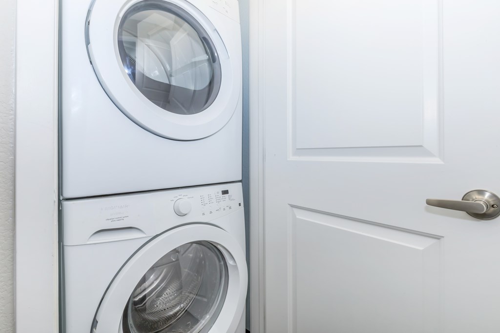 A white door is next to a stack of white washing machines.
