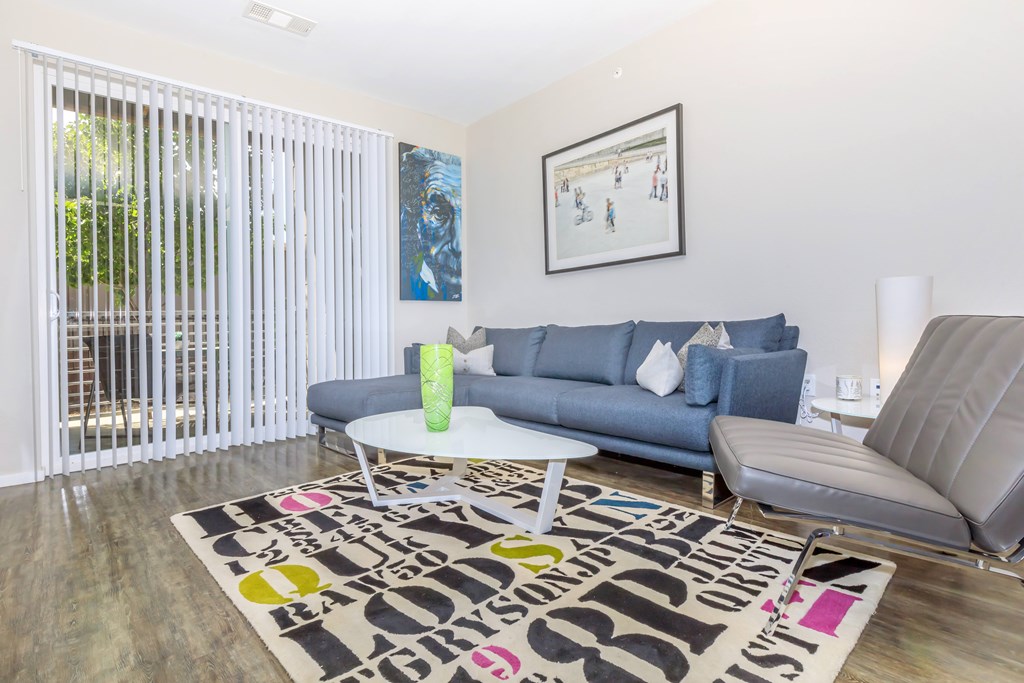 A living room with a grey couch, a white coffee table, and a rug with the word "love" written on it.