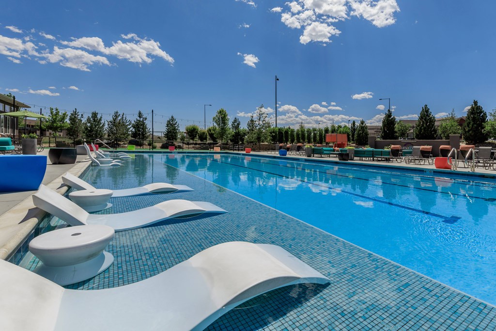 A large swimming pool with chairs in the pool.