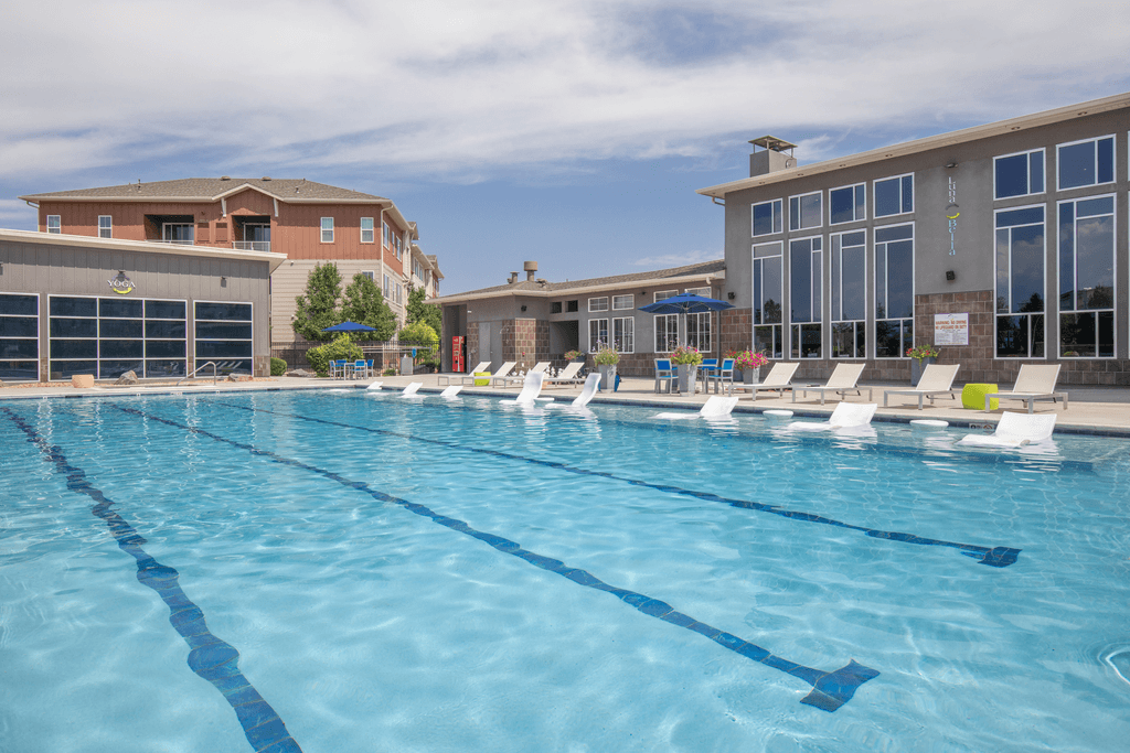 A large swimming pool with lane dividers and a building in the background.