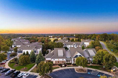 A sunset view of a residential area with houses and parked cars.