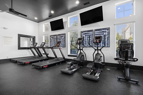 A gym with treadmills, exercise bikes, and a television.