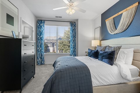 A bedroom with a large bed and a ceiling fan.