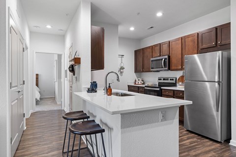 A modern kitchen with a white countertop and stainless steel appliances.