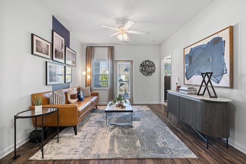A living room with a brown couch, a coffee table, and a large abstract painting on the wall.