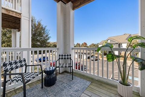 A balcony with a black and white checkered chair and a potted plant.