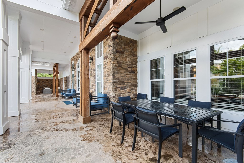 a patio with a long table and chairs and a stone fireplace