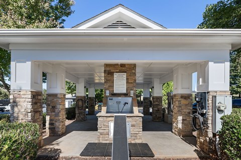 A white building with a black mat in front and a sign on the wall.